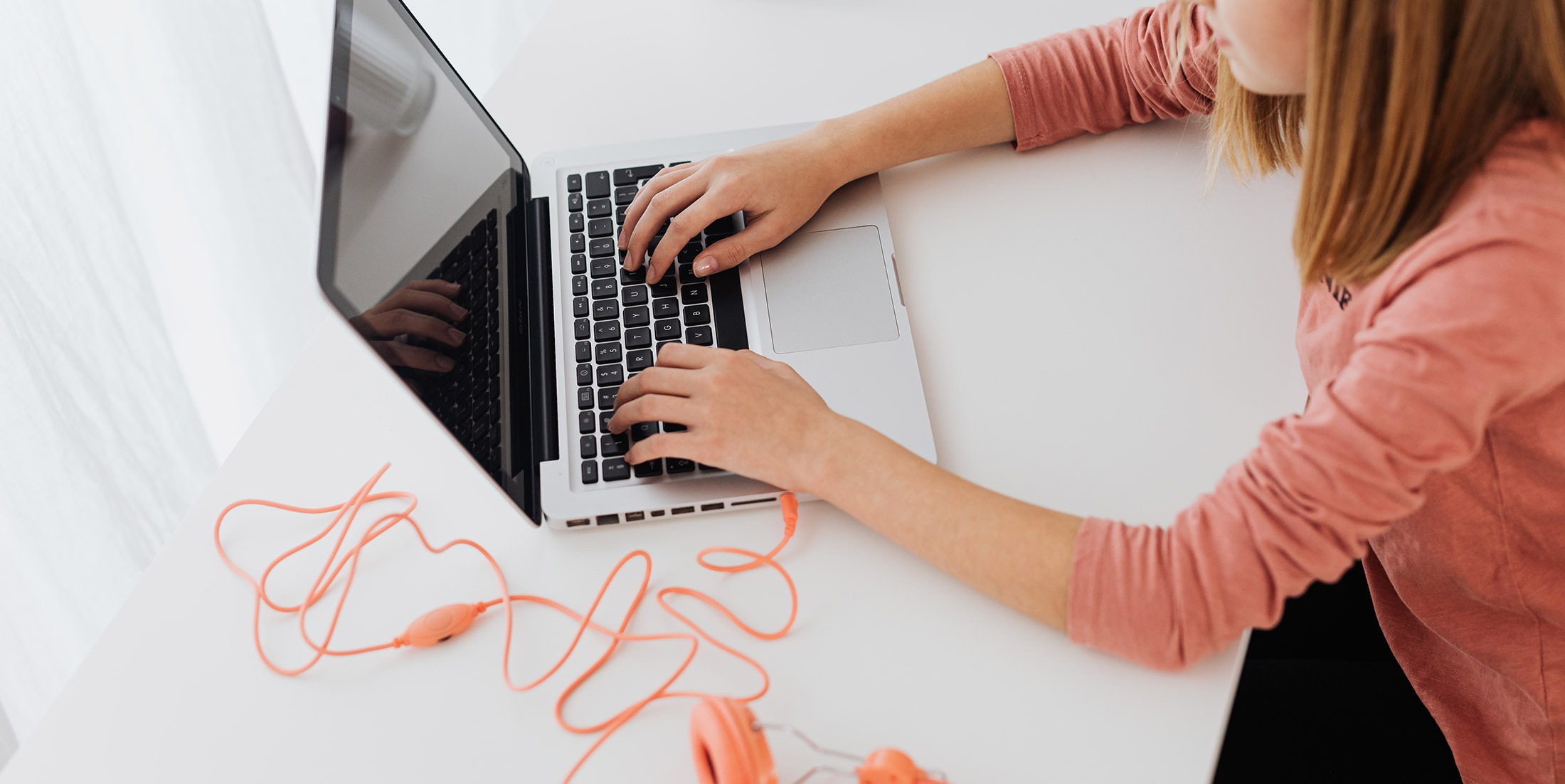 Student at a laptop with headphones plugged in