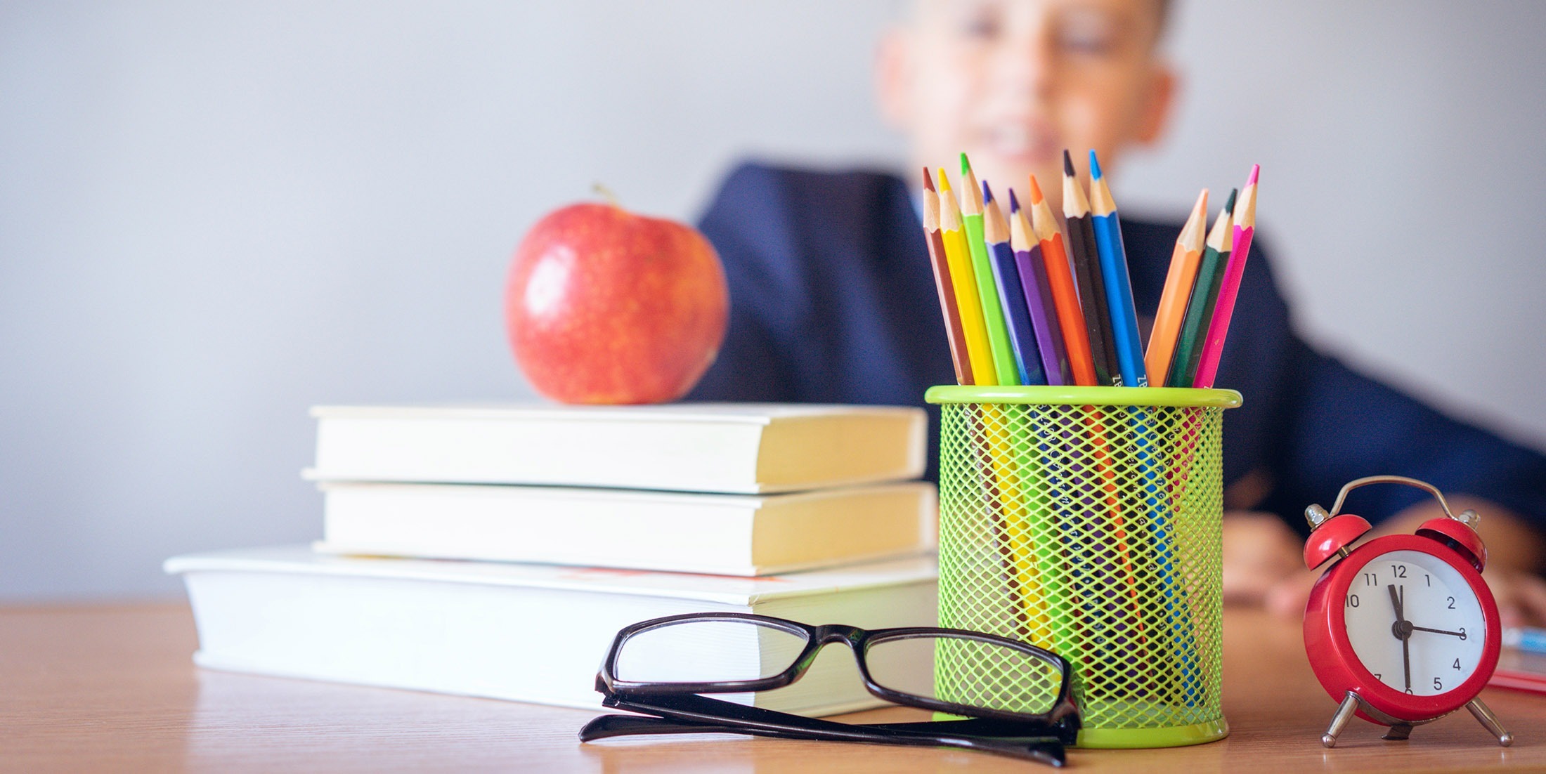 Student at desk with apple, books, pencils, glasses and a timer