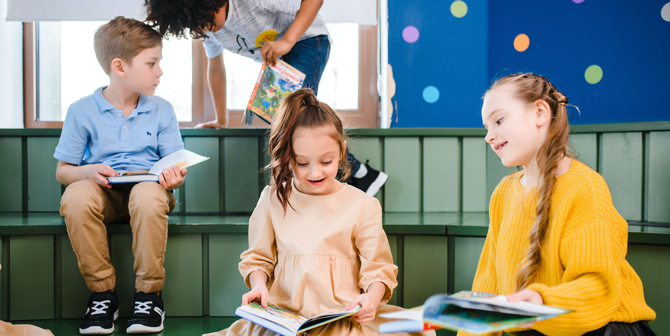 Four young students reading and talking in a classroom
