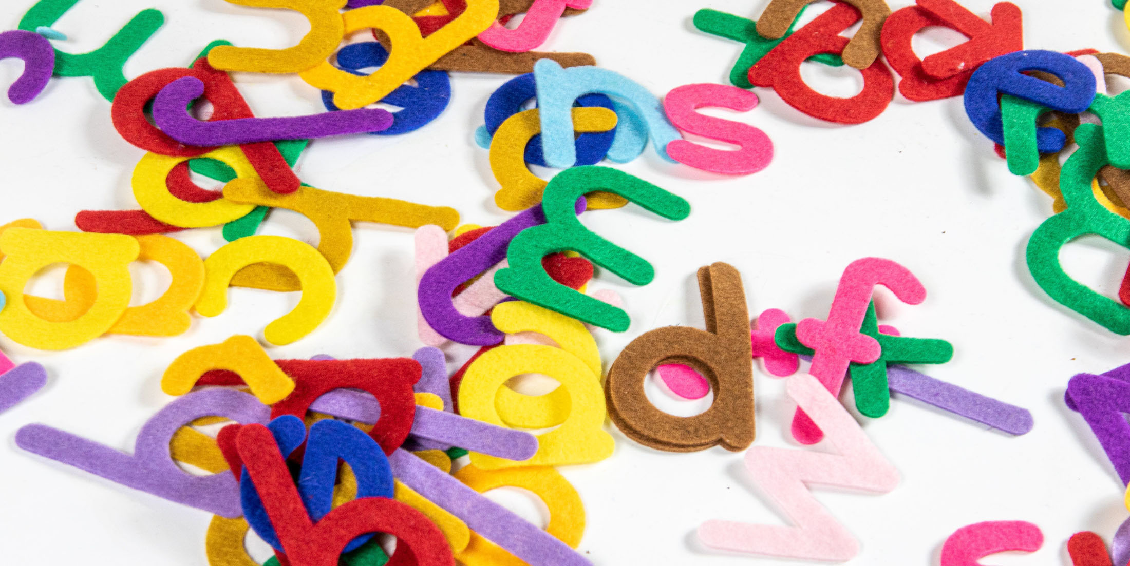 Fabric letters of different colors scattered on a surface