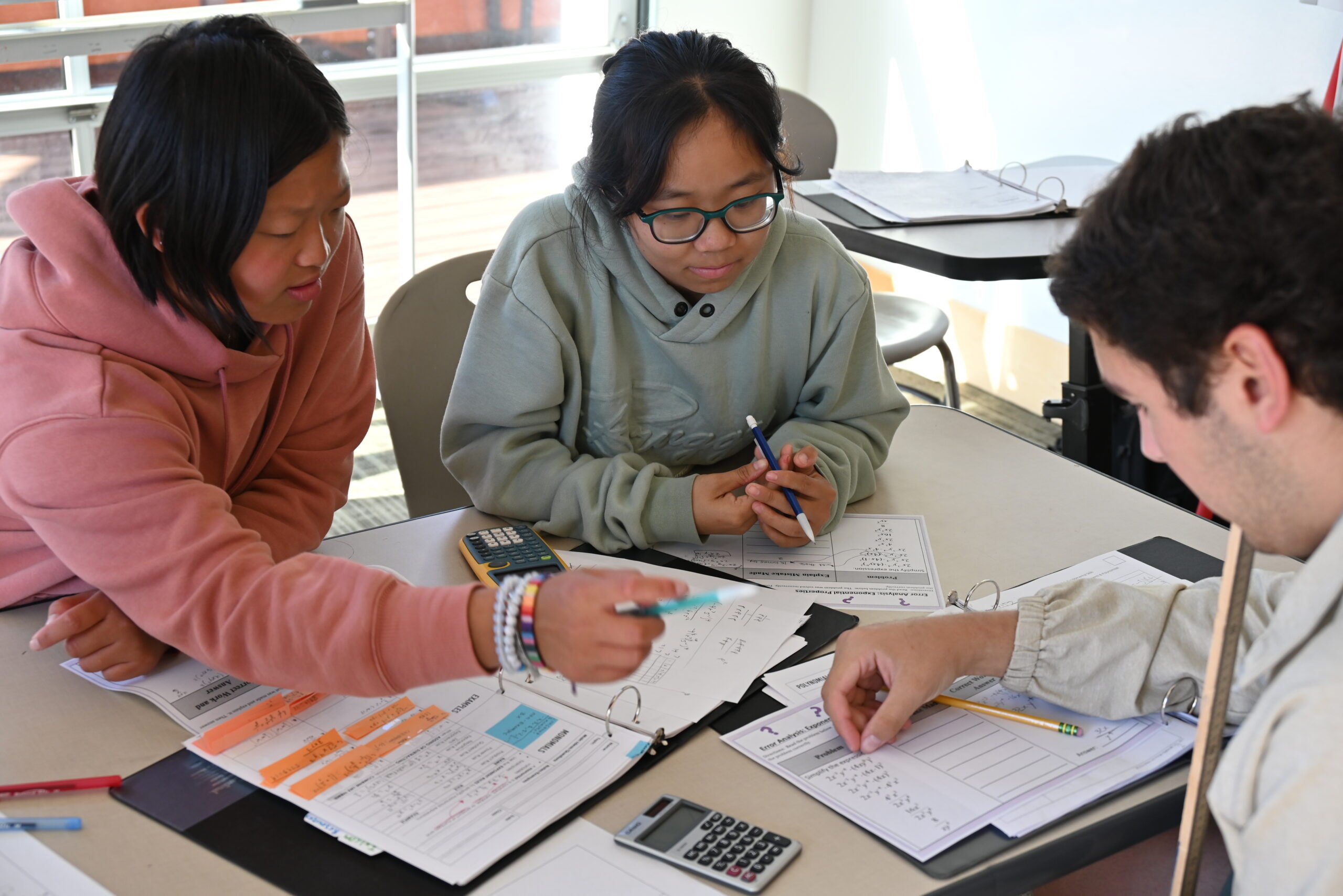 Three high school students collaborate on a math worksheet together