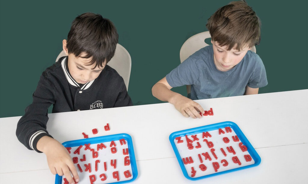 Students working with letters on trays